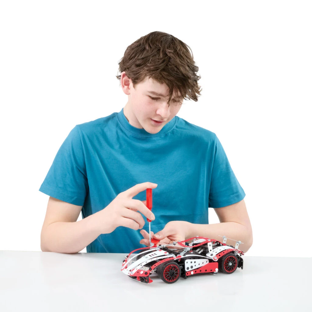 Een jonge bouwer werkt geconcentreerd aan zijn Meccano Supercar
