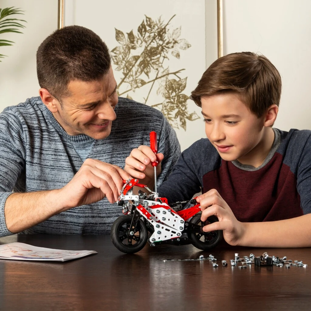 Een vader en zoon bouwen samen aan een Meccano-model aan de keukentafel